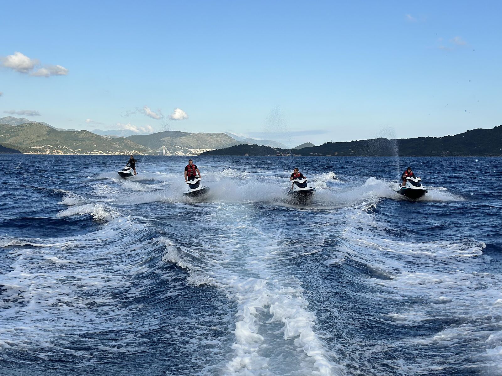 Jet ski riders following a guide into a hidden cove near Dubrovnik